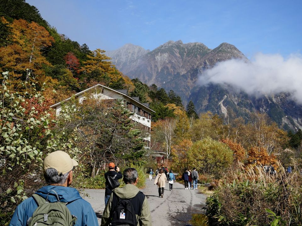 紅葉の山道を歩くシニア