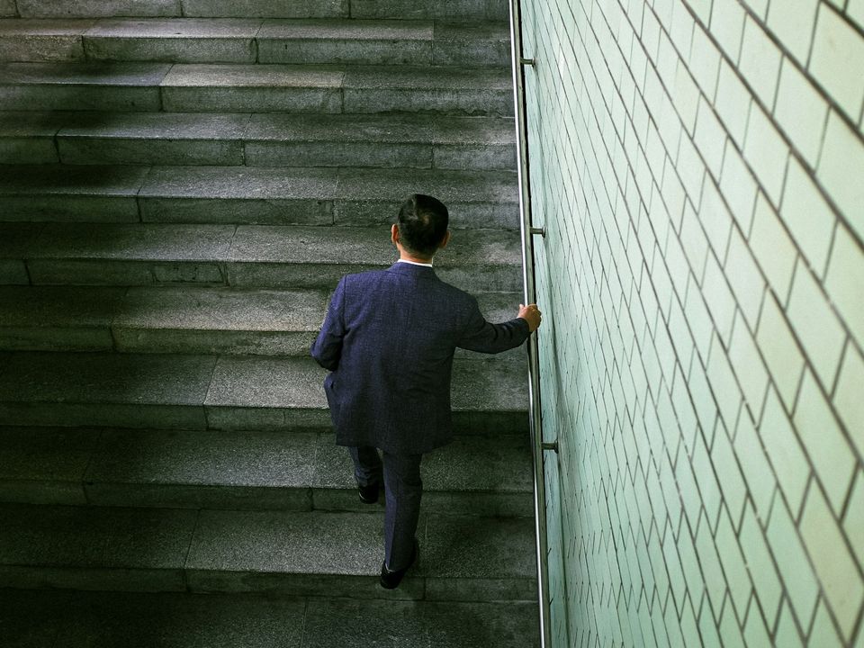 手すりをつかんで階段を上る男性